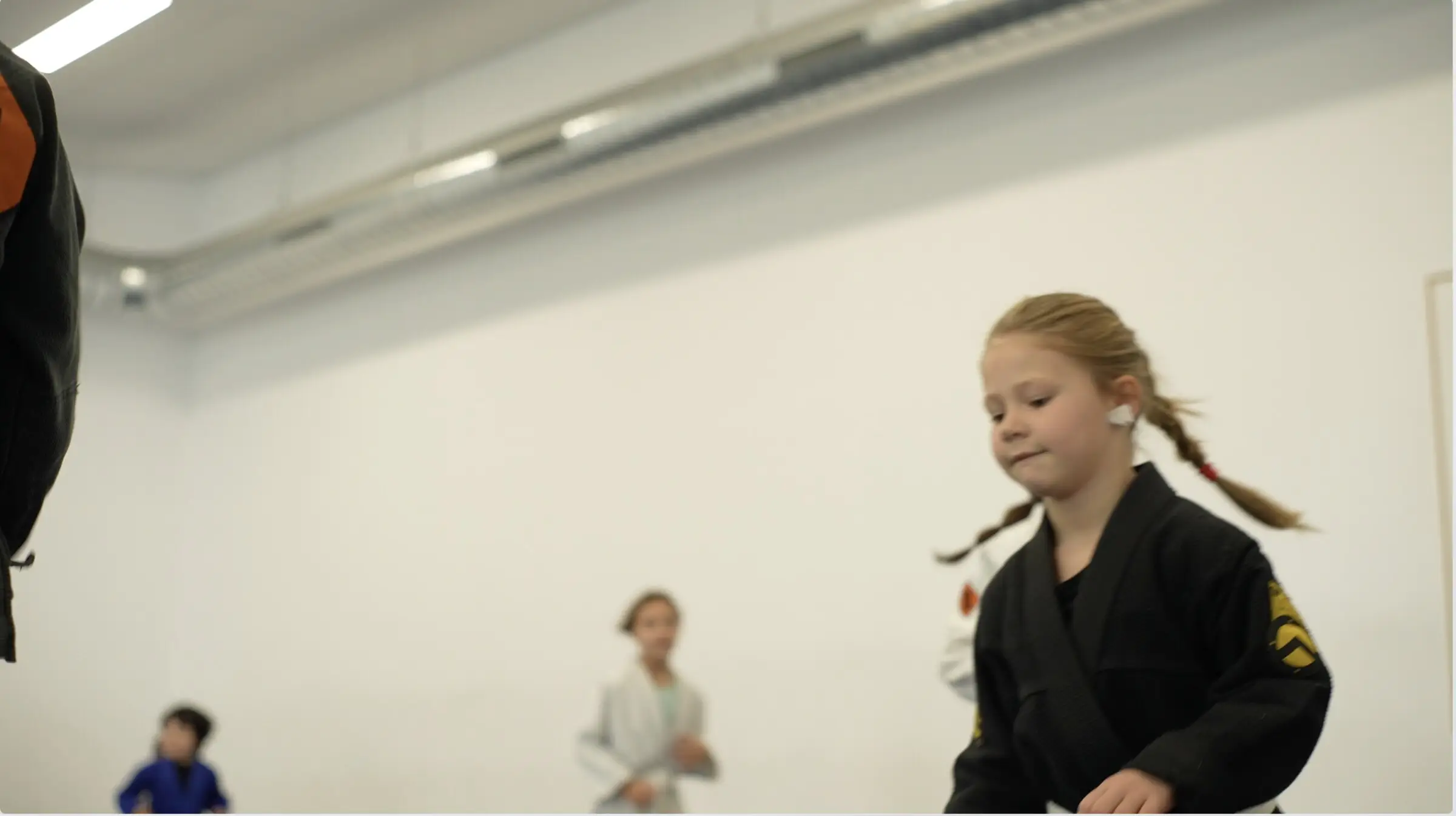 Une fillette en kimono noir dans le dojo