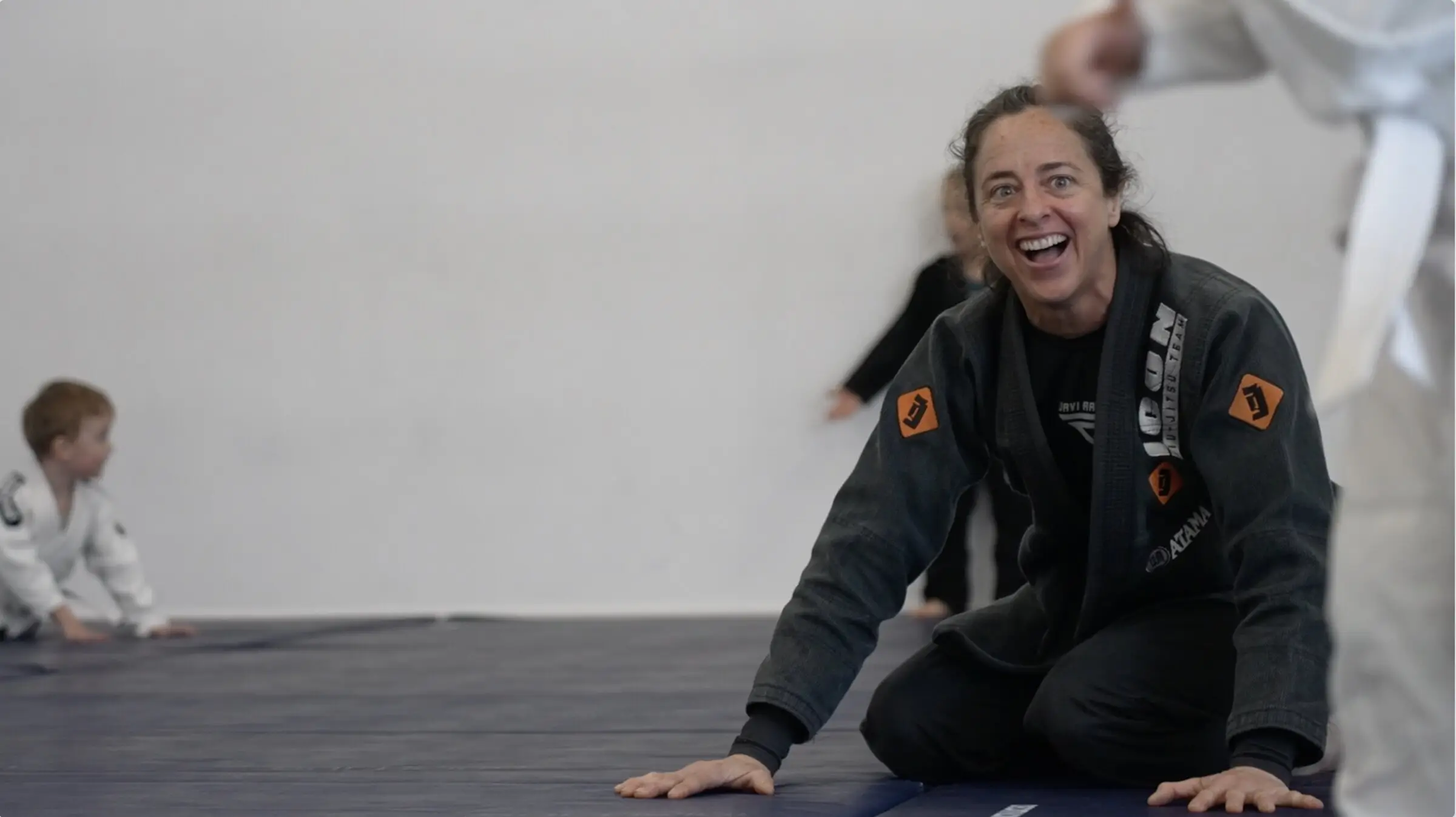 Une professeure souriante, à genoux sur le tatami